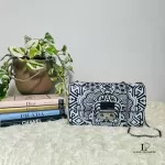Furla black and white wallet on chain with chain strap, styled on a shelf