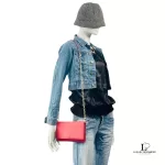 Tory Burch coral pink leather clutch with gold-tone chain, worn crossbody on a mannequin with a denim jacket