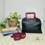 Furla tri-colour two-way handbag in black, white and maroon, styled on a shelf with strap