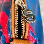 Desigual blue multicolour painterly tote bag, close-up of zip and letter charm