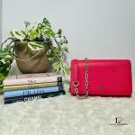 Tory Burch coral pink leather clutch with gold-tone chain, styled on a shelf