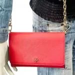 Tory Burch coral pink leather clutch with gold-tone chain, worn crossbody