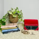 Furla red suede and leather clutch with gold-tone chain, styled on a shelf