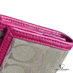 Coach signature monogram flap wallet with fuchsia trim, close-up of the monogram and fuchsia trim