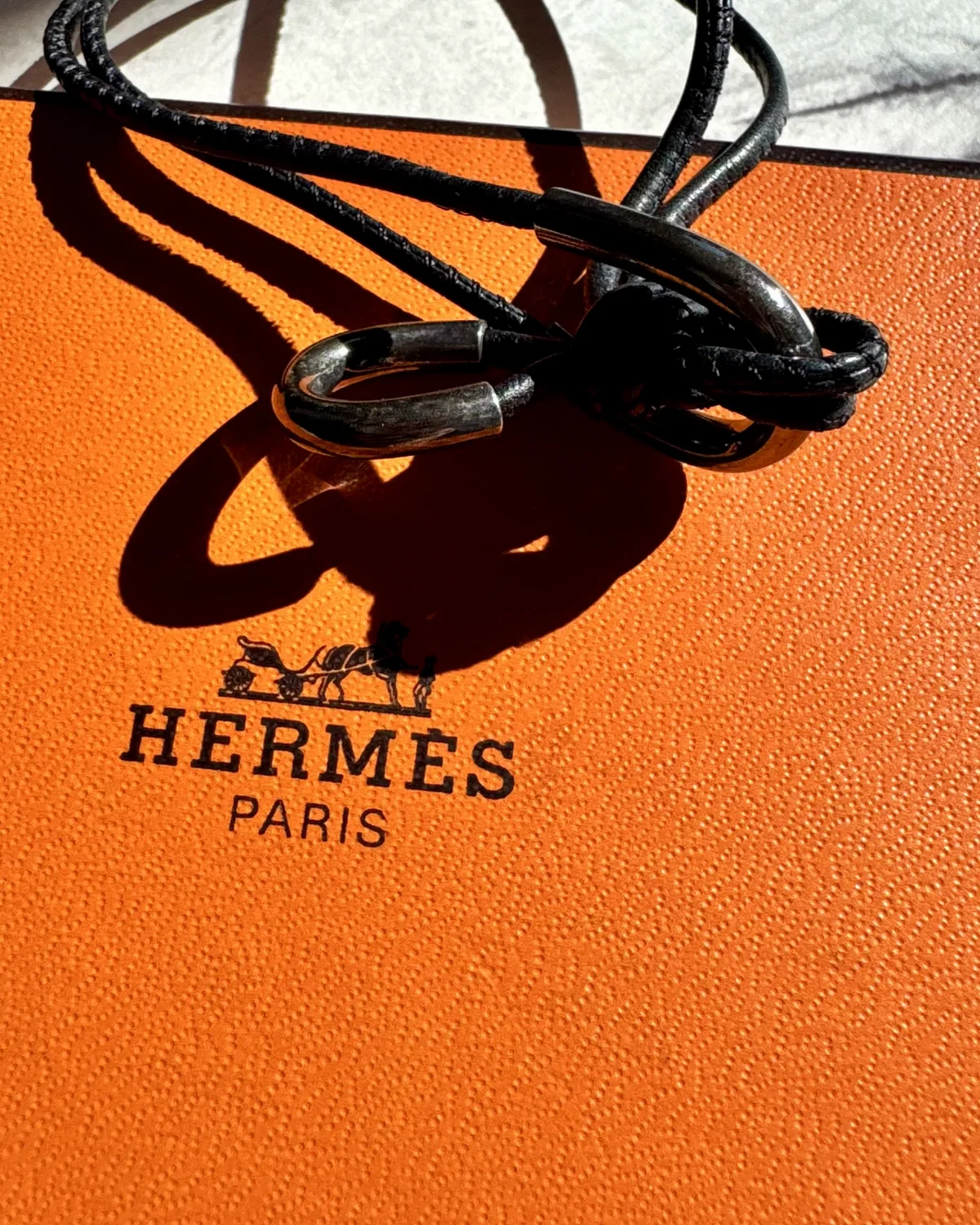 Hermès leather bracelet detail resting on an orange gift box