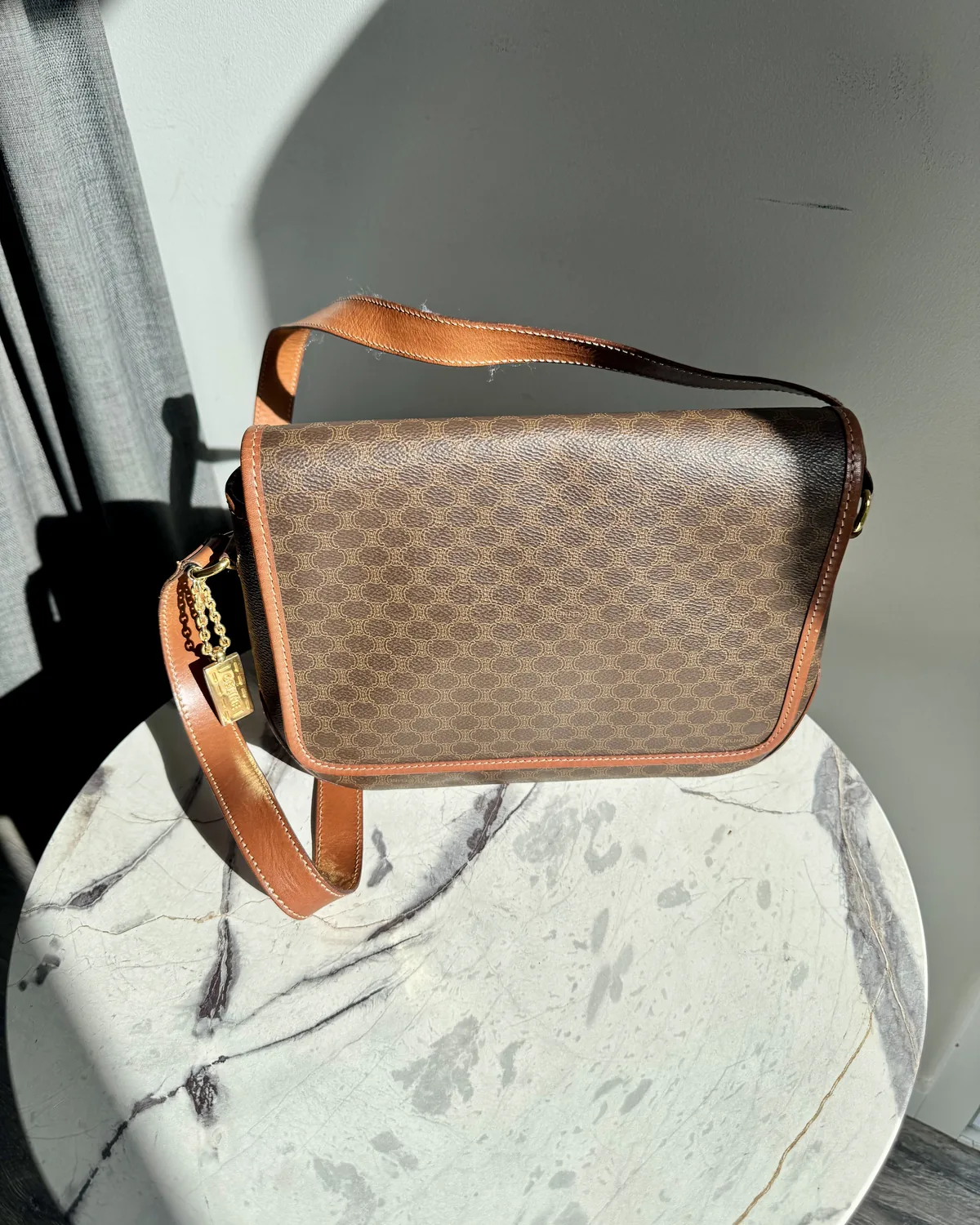 Vintage monogram leather crossbody bag on a marble pedestal